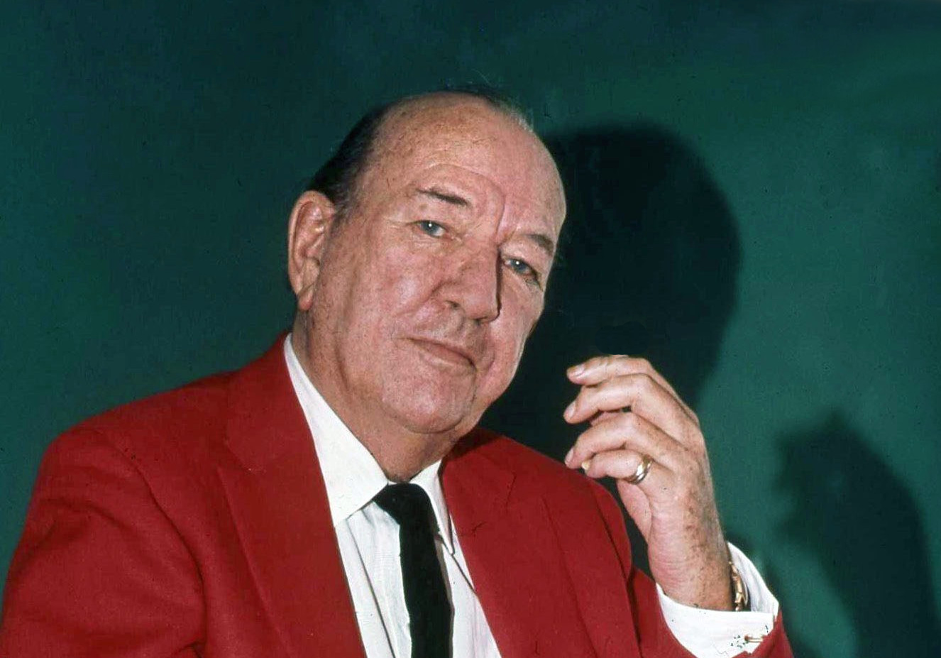 Portrait of Sir Noel Coward wearing a red blazer