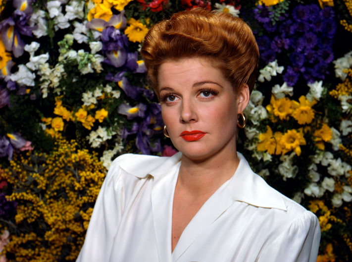 Ann Sheridan posing by colorful flowers
