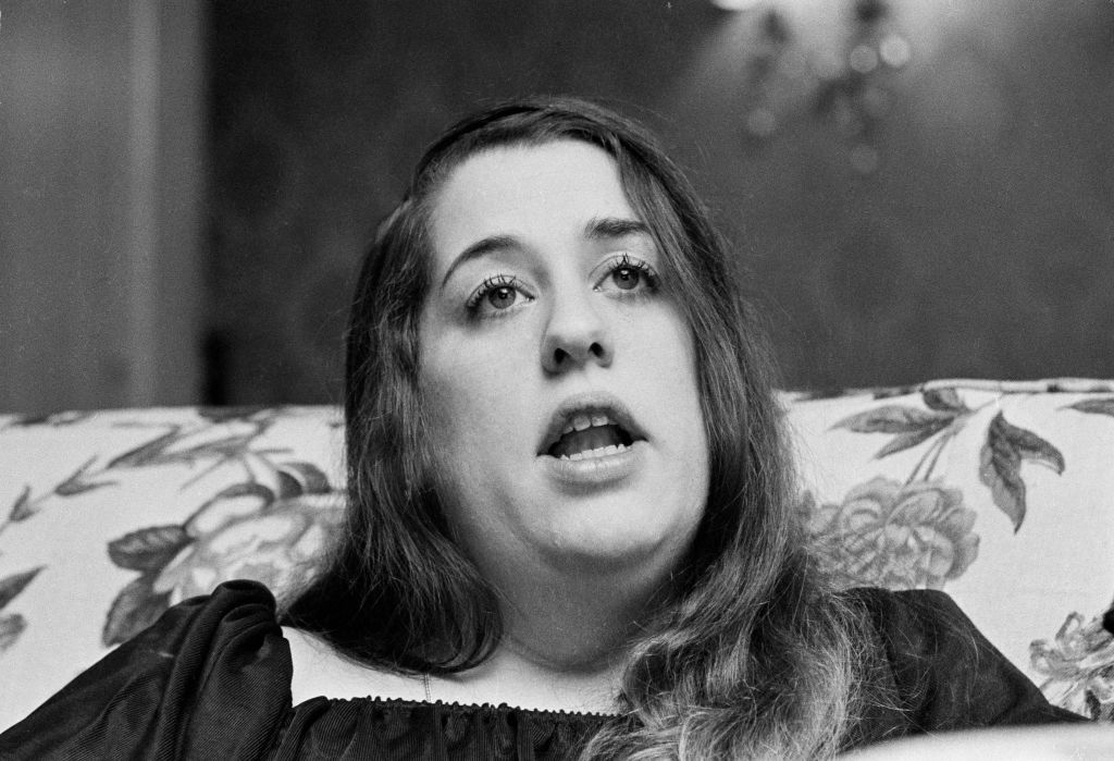 American singer Cass Elliot sitting on couch speaking to someone