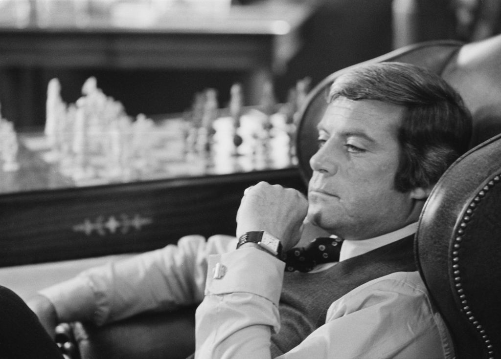 English actor Oliver Reed sitting on an armchair