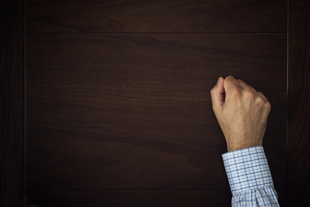 Male hand is knocking on wooden door