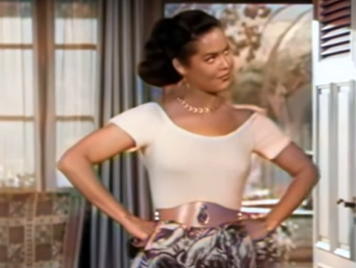 Screenshot of Dona Drake looking at side with her arms on hips - from Kansas City Confidential (1952)