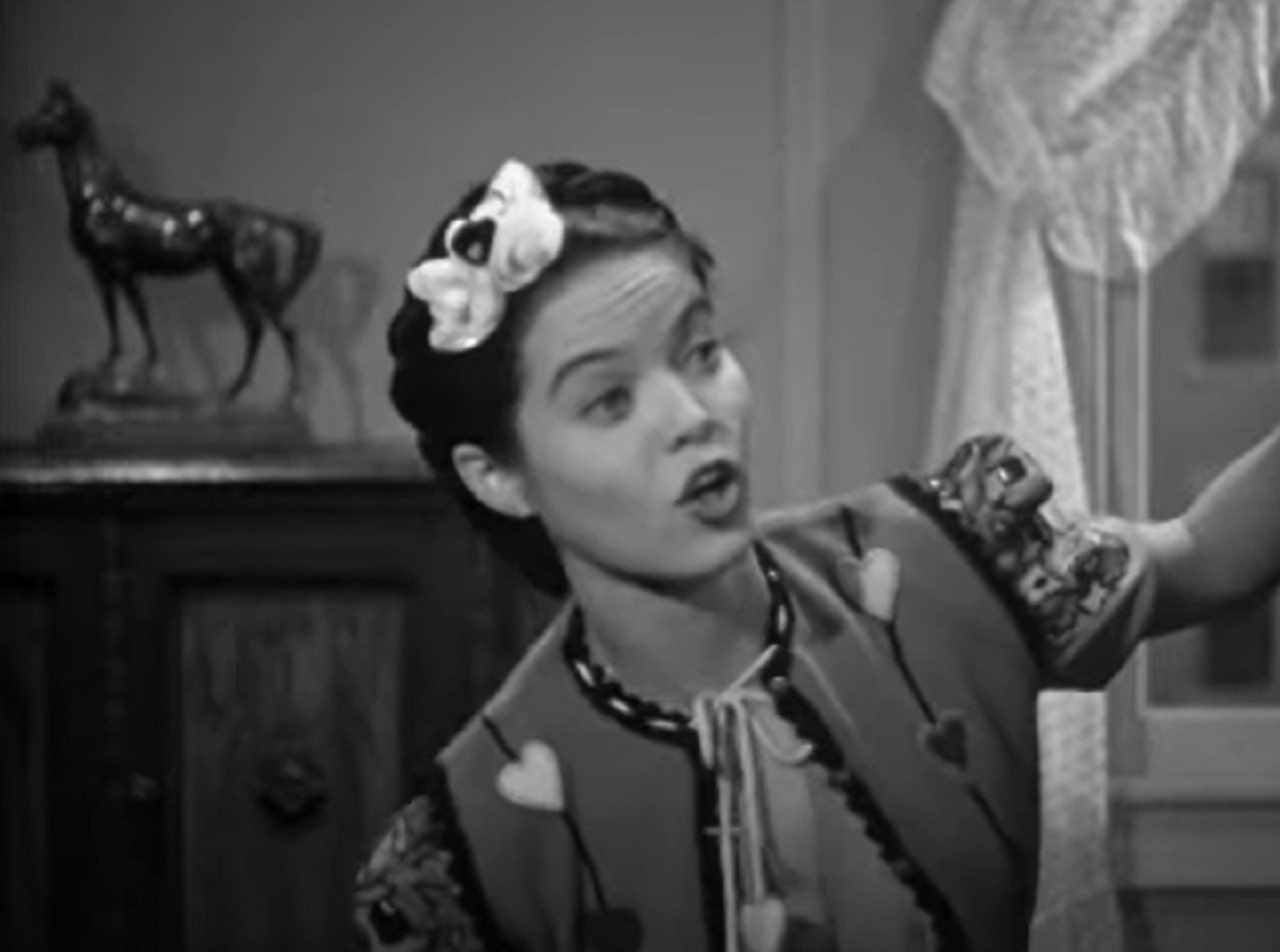 Screenshot of Dona Drake looking at side and talking - from Rita Rio and Her Orchestra (1939)