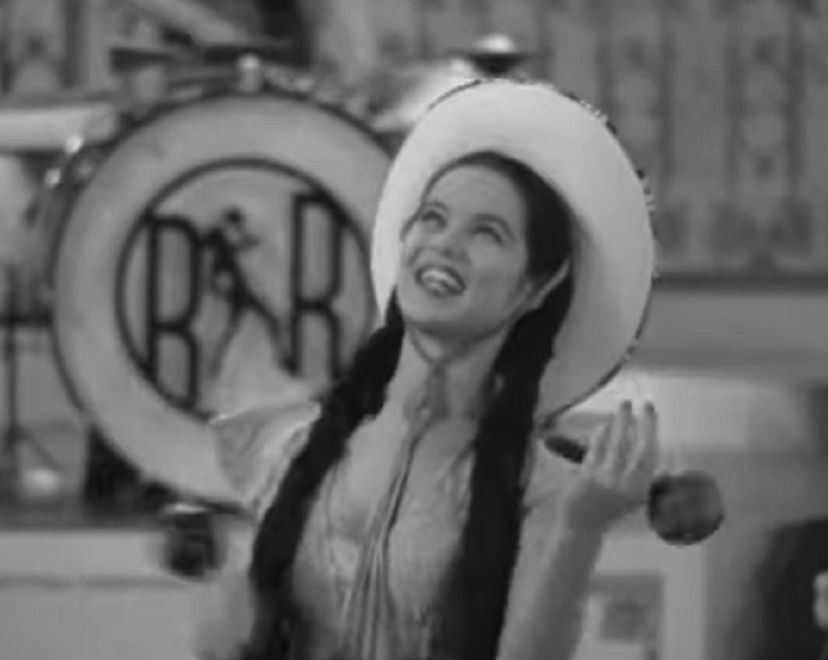 Screenshot of Dona Drake wearing white hat and smiling - from Rita Rio And Her Orchestra (1939)