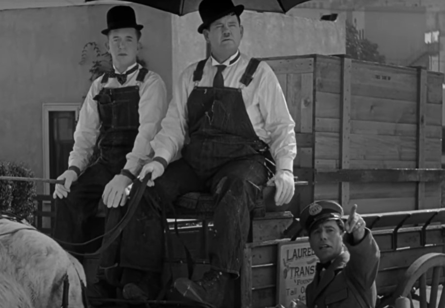 Laurel and Hardy sitting at a carriage with a horse