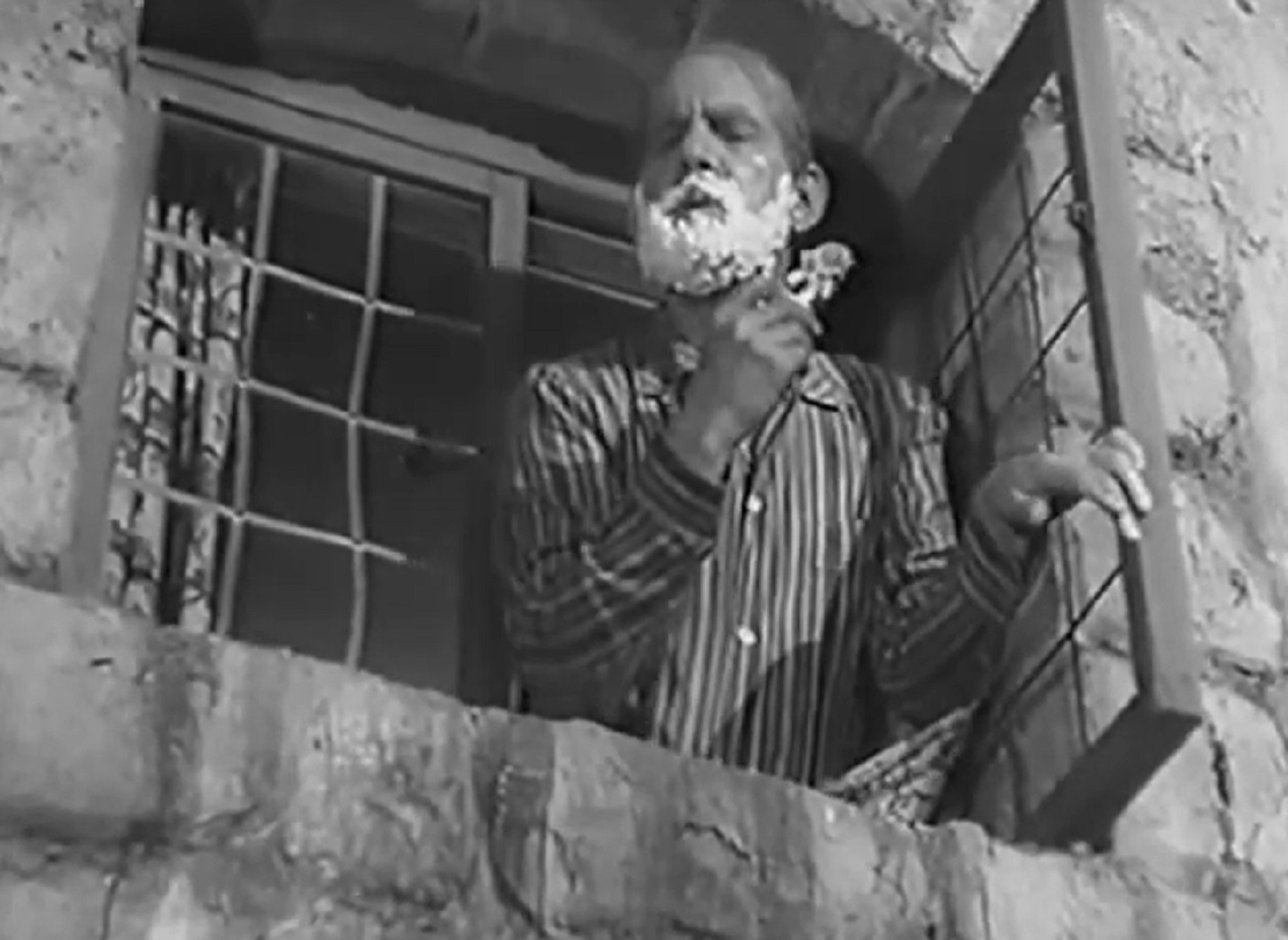 Screenshot of Will Hay shaving on the window - from Ask a Policeman (1939)