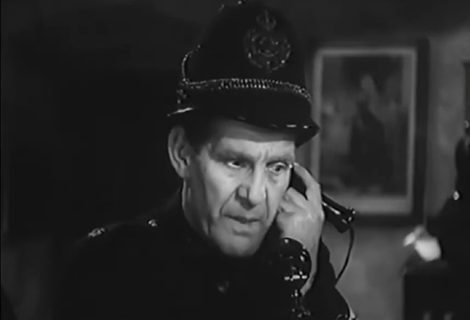 Screenshot of Will Hay in police uniform talking on the phone - from Ask a Policeman (1939)