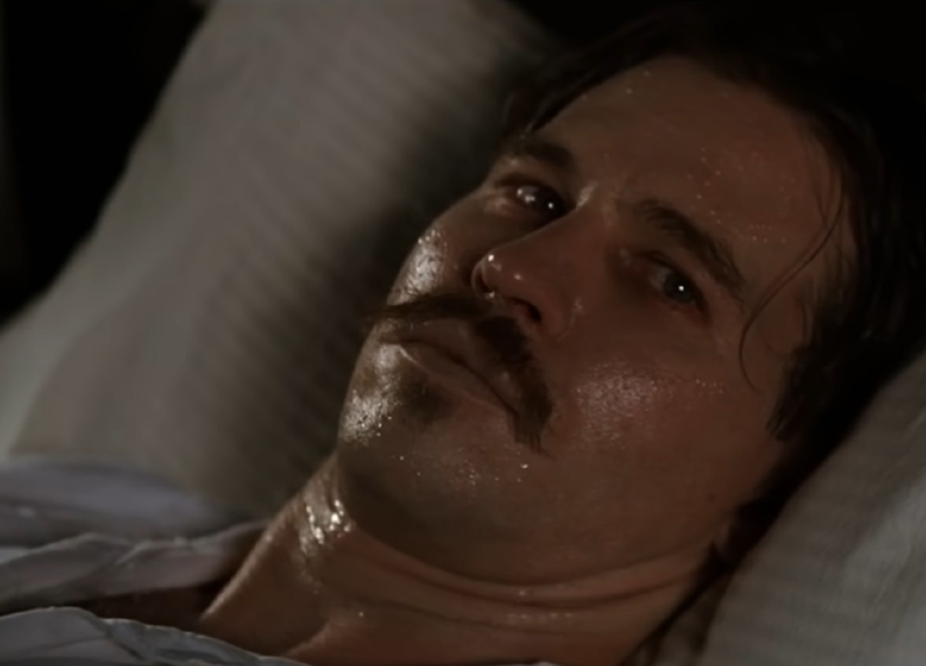 Screenshot of Val Kilmer laying sick in bed - from Tombstone (1993)