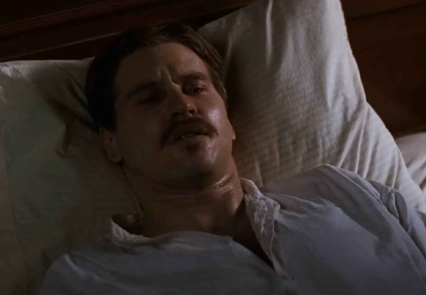 Screenshot of Val Kilmer laying sick in bed - from Tombstone (1993)