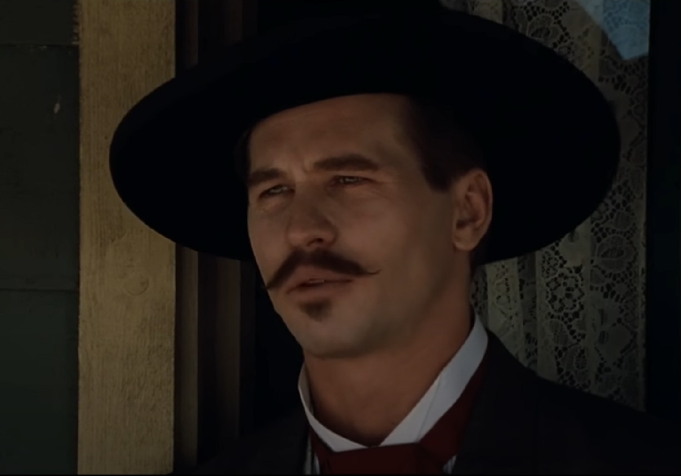 Screenshot of Val Kilmer wearing hat and looking at side - from Tombstone (1993)