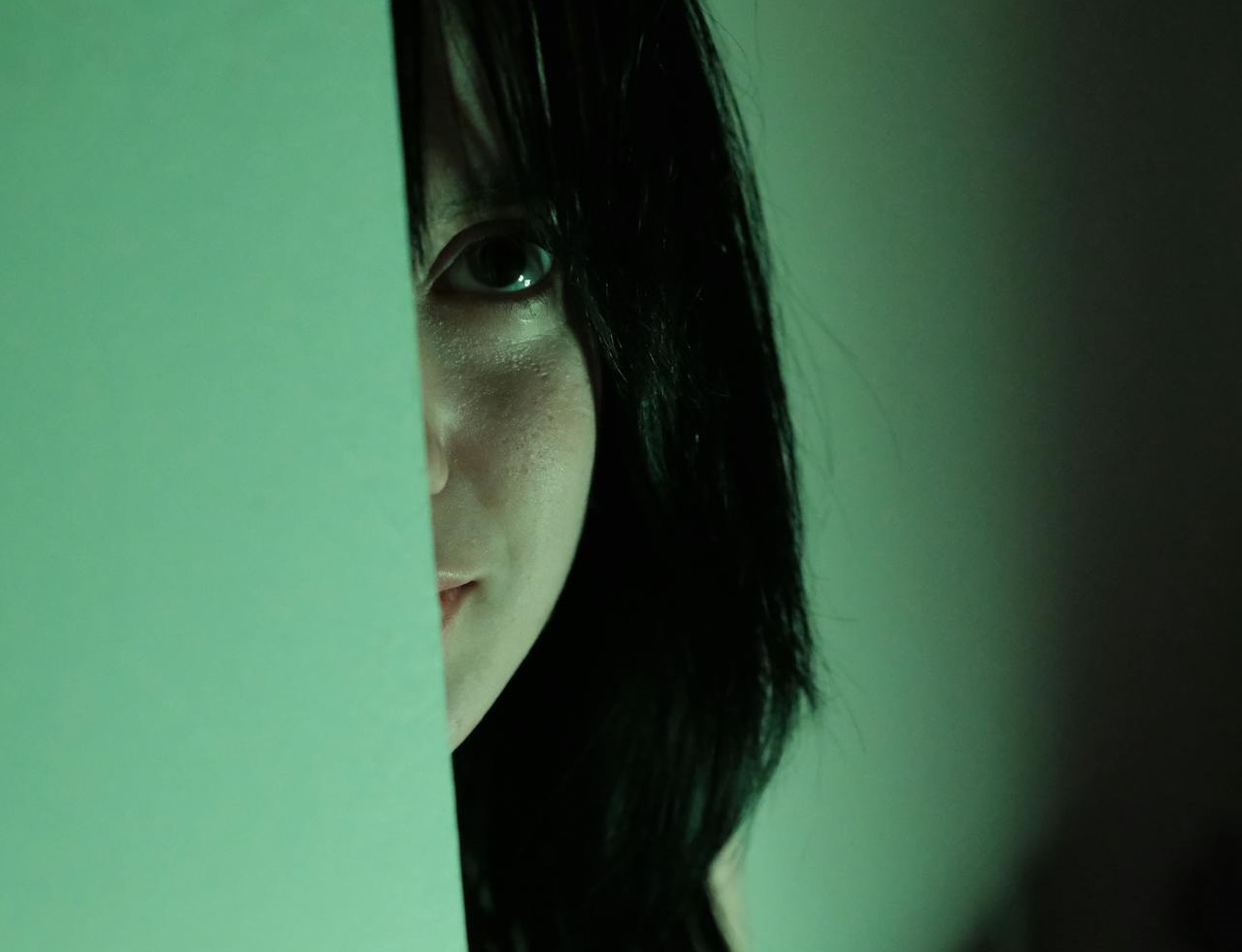 Woman Hiding behind green Wall