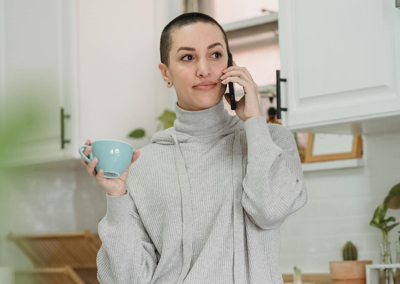Woman talking on smartphone and drinking cup of coffee.
