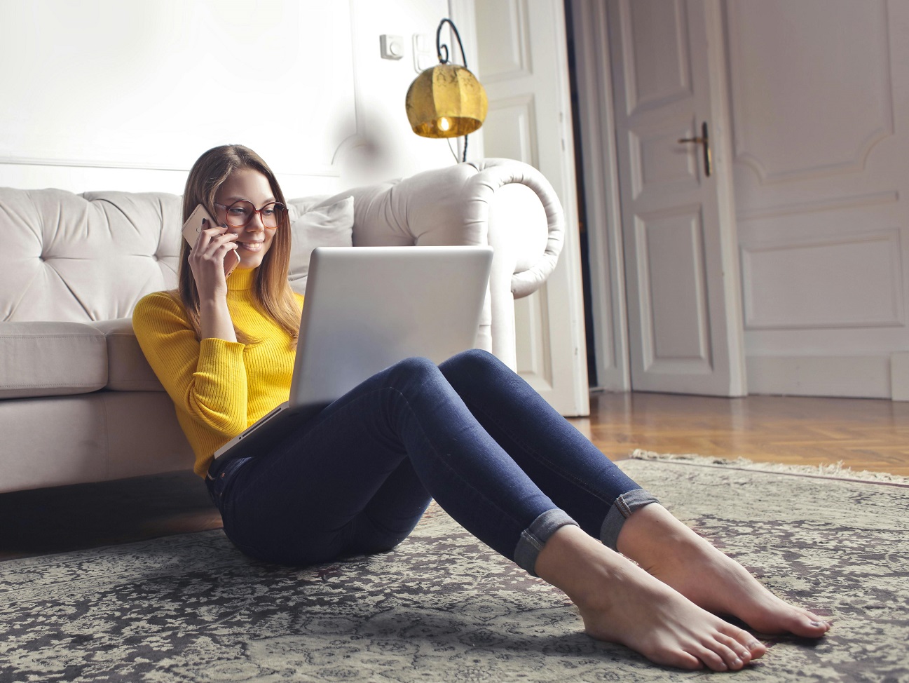 Happy adult woman talking on phone and using laptop