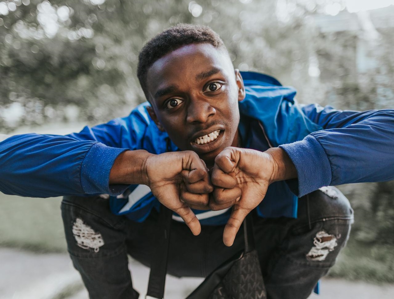 Man in Blue Jacket and Black Pants Flashing the Thumbs Down