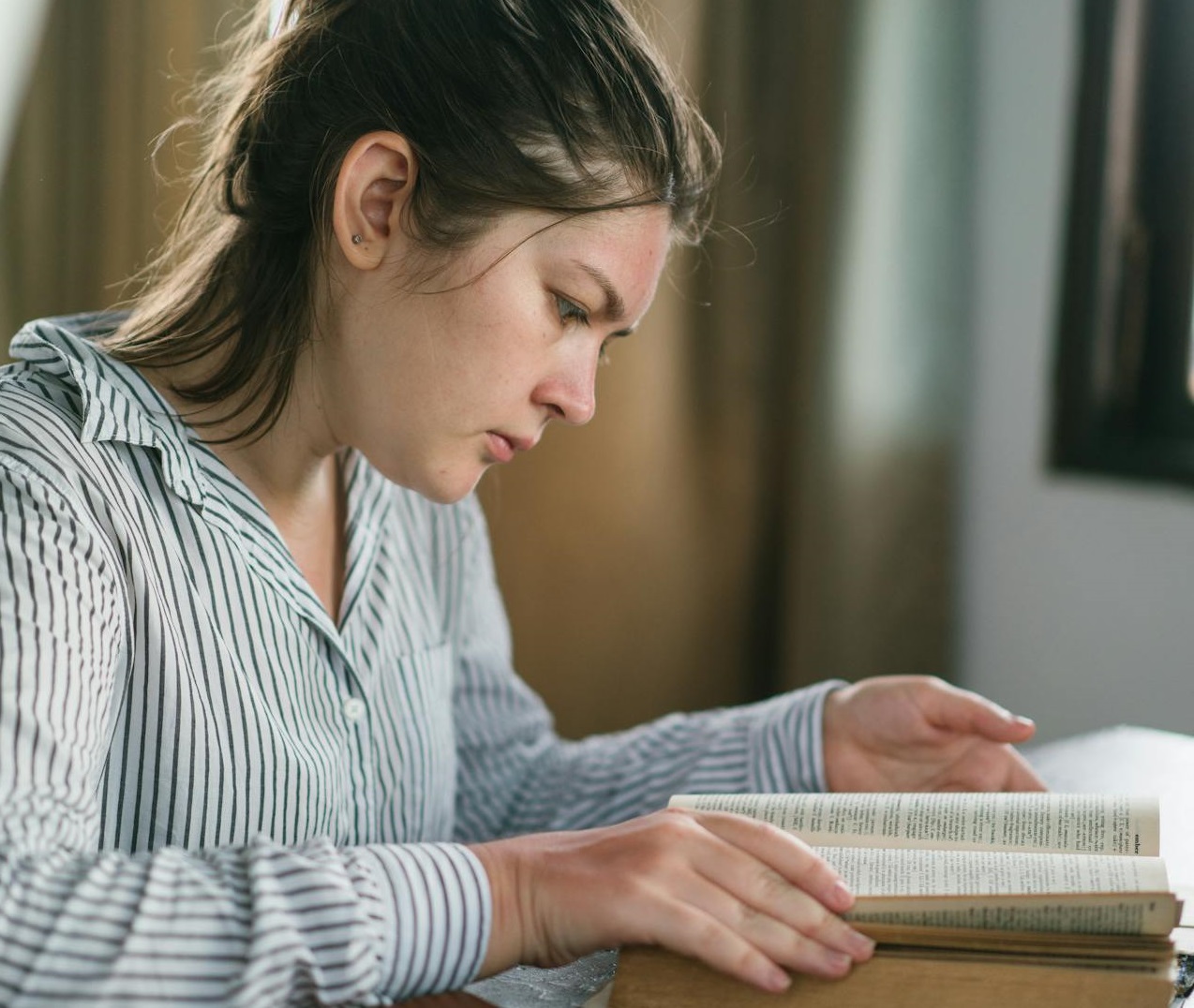 Woman looking at dictionary and sitting at table.