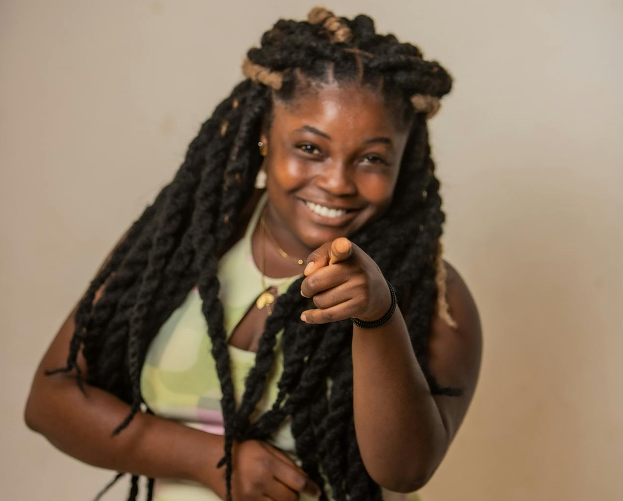 Woman is smiling and Pointing at the Camera.