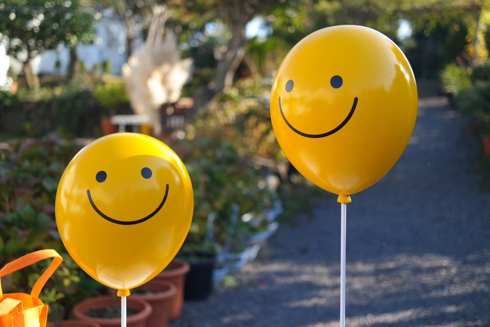 Two yellow balloons decorated with smileys