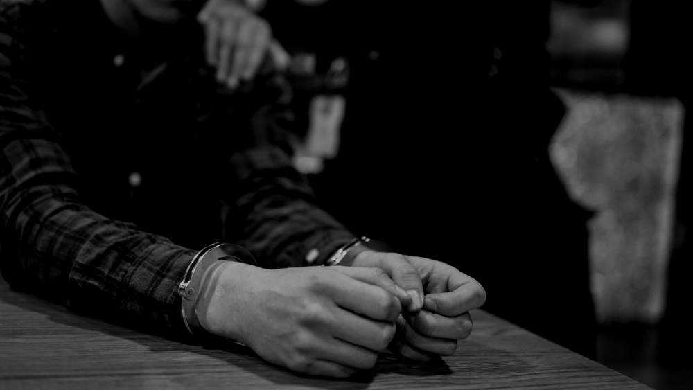 Criminal arrested and handcuffed while police grab shoulder