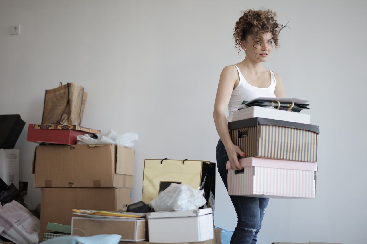 woman carrying stack of cardboard boxes