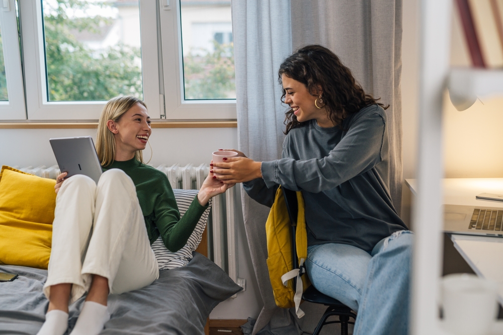 College student is passing a coffee cup to her friend