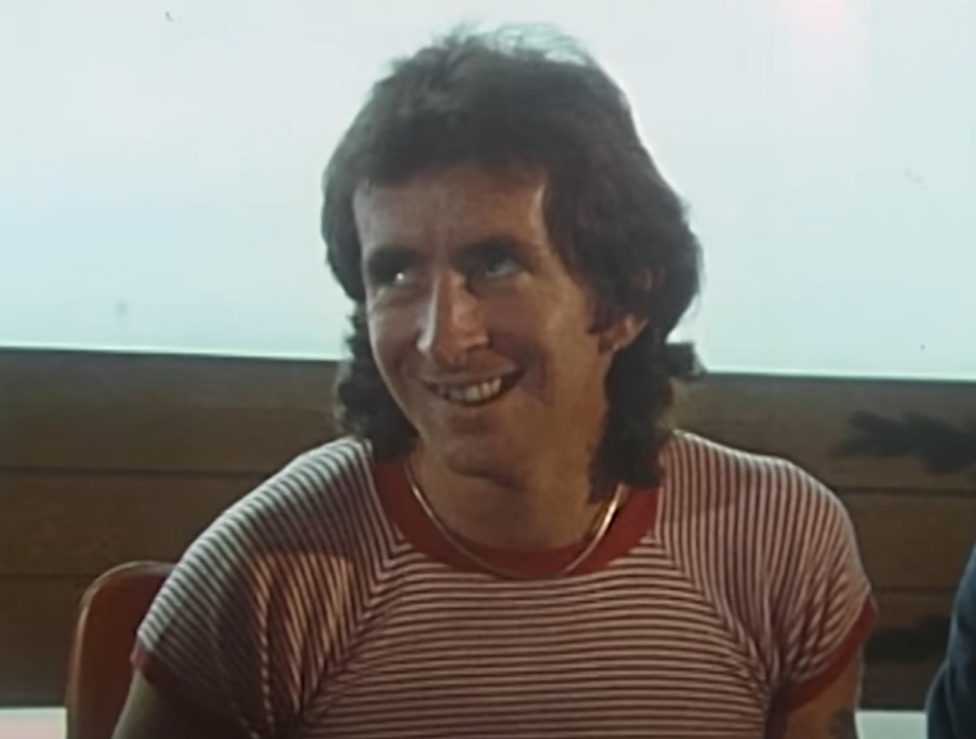 Screenshot of Bonn Scott smiling at camera from - On The Brink (2022)