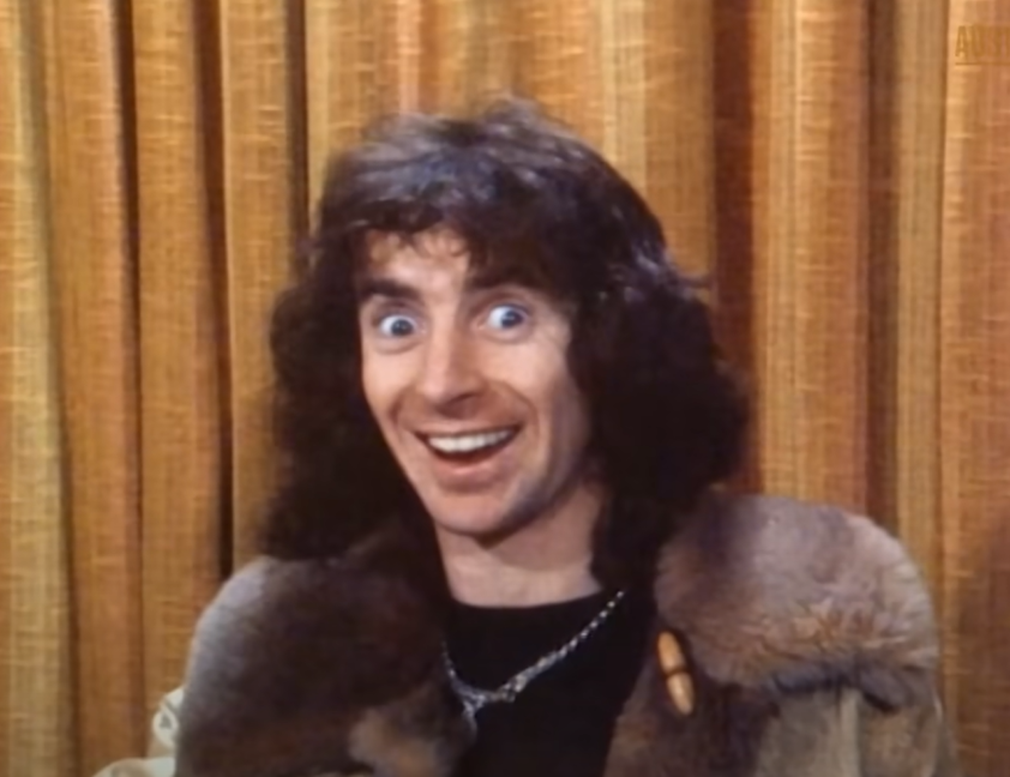 Screenshot of Bonn Scott smiling at camera from - On The Brink (2022)