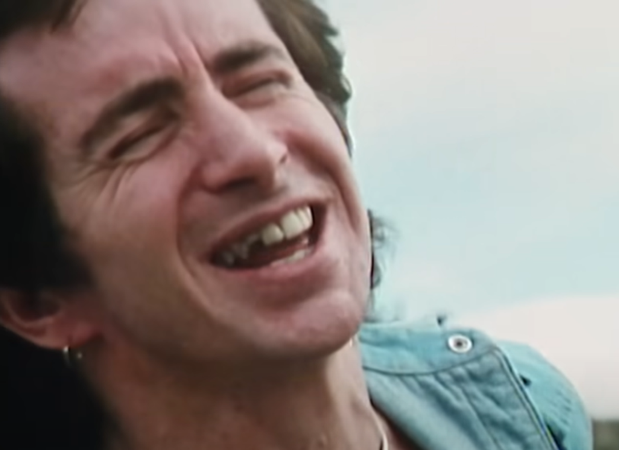 Screenshot of Bonn Scott smiling at camera from - On The Brink (2022)