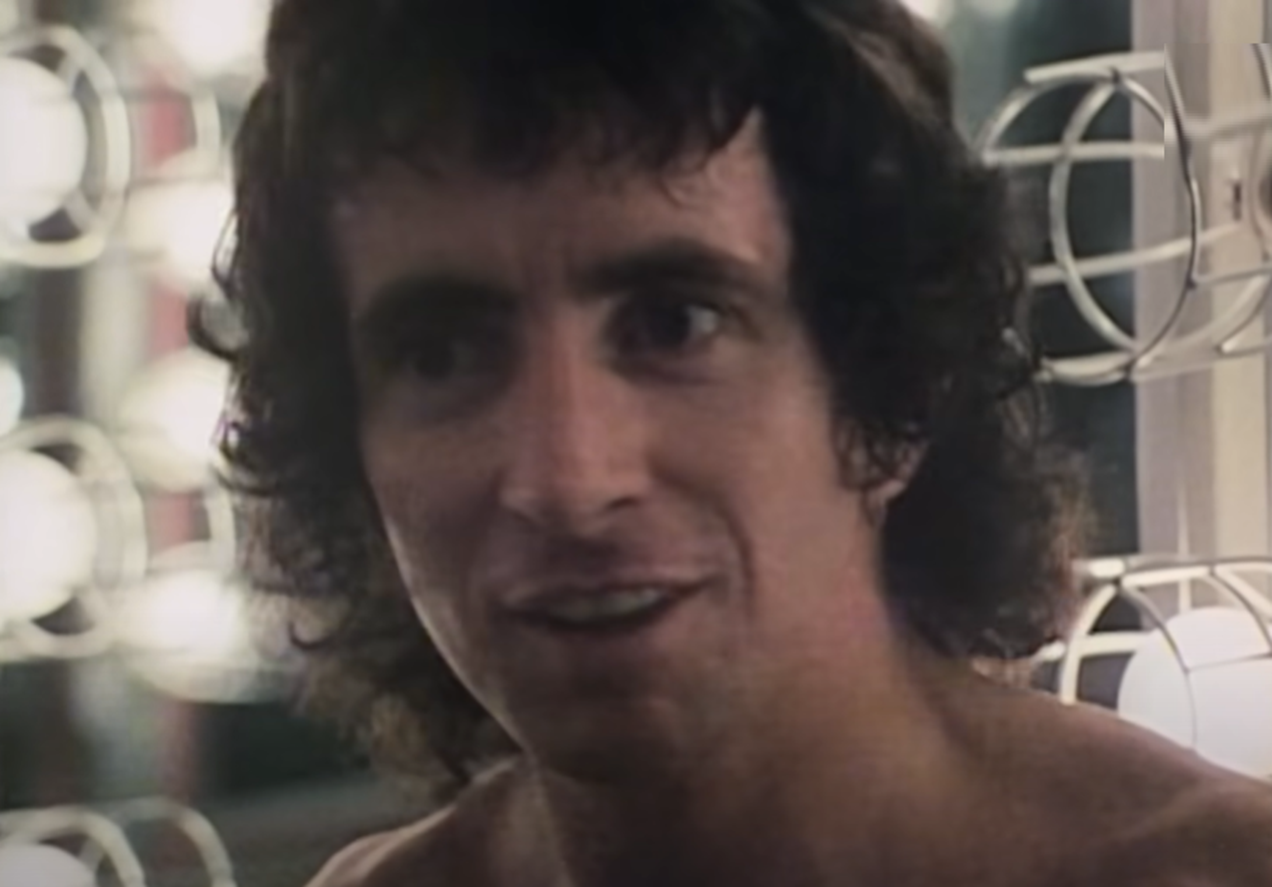 Screenshot of Bonn Scott smiling at camera from - On The Brink (2022)