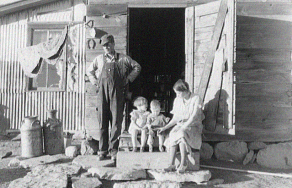 A farmer and his family in front of home