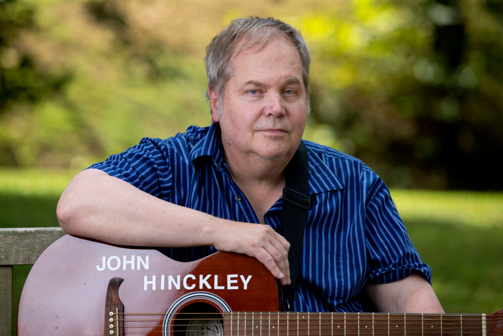 John Hinckley Jr. sits for a portrait with his guitar in Williamsburg, Virginia
