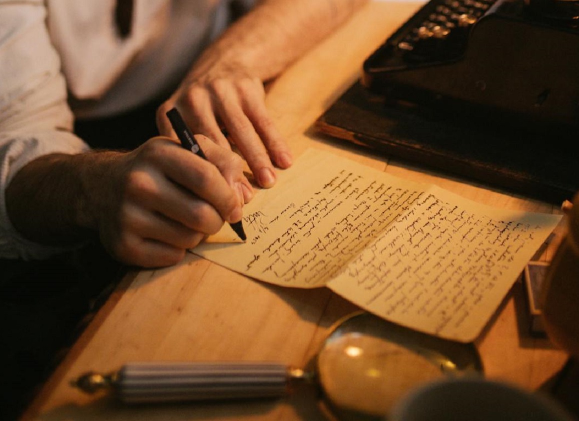 Man Writing on a Piece of Paper.