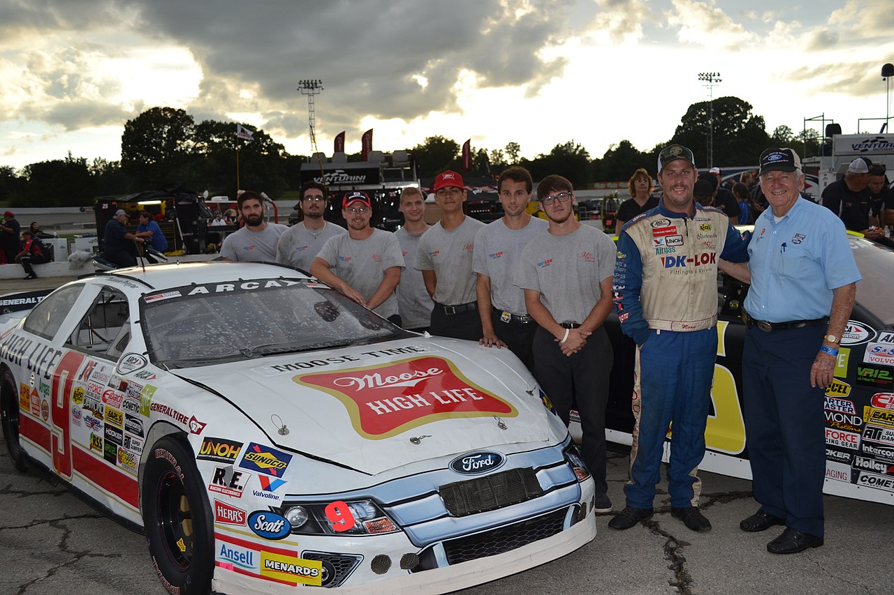 NASCAR drivers posing with a car