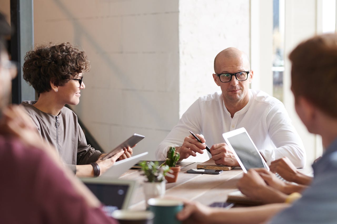 Photo of Man Sitting in Front of People - Office meeting