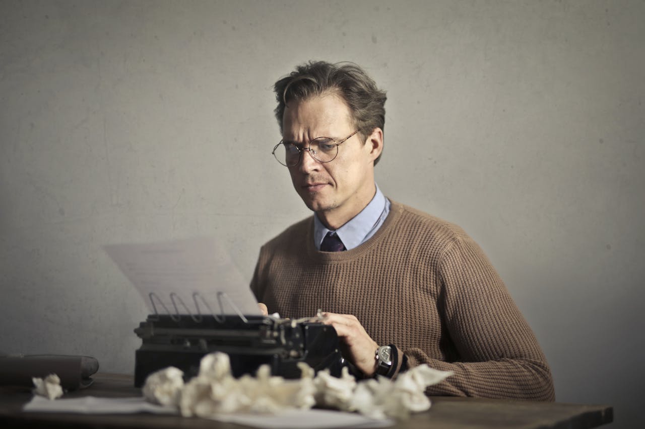 Adult frowned male writer working on typewriter