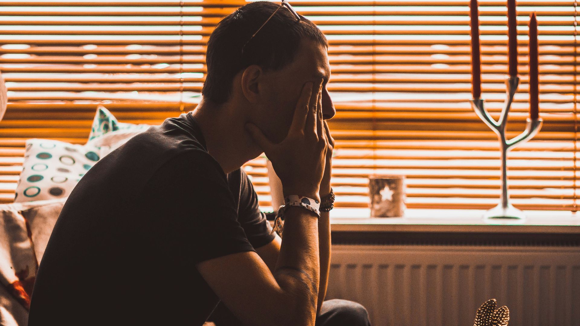 man sitting on chair covering his eyes