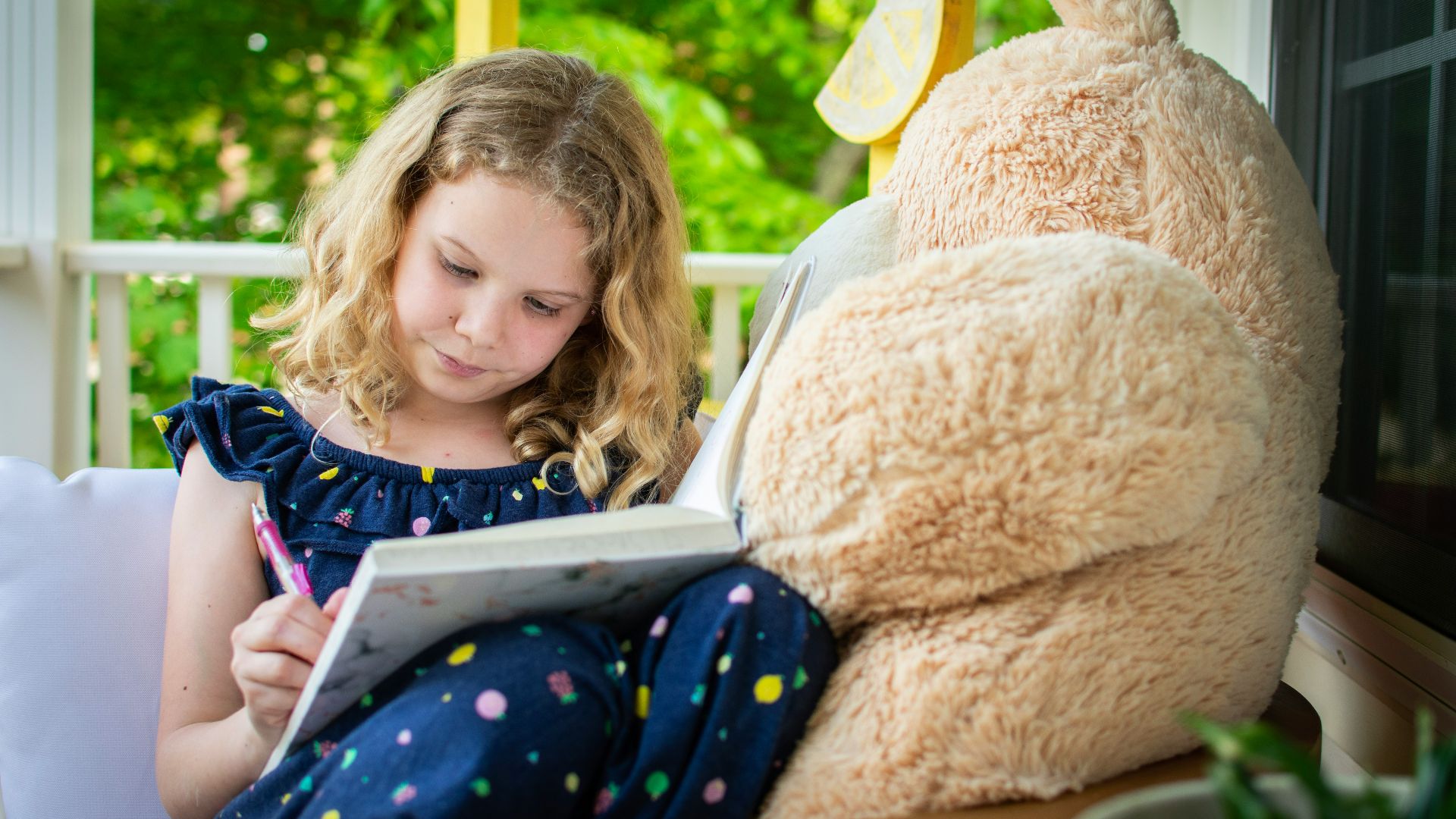 girl in blue and white long sleeve shirt sitting on brown bear plush toy