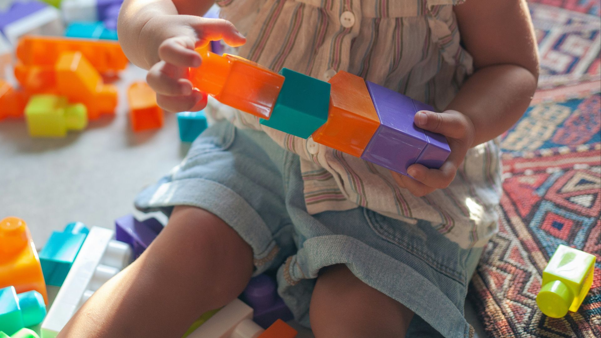 girl in brown button up shirt holding blue and orange plastic toy