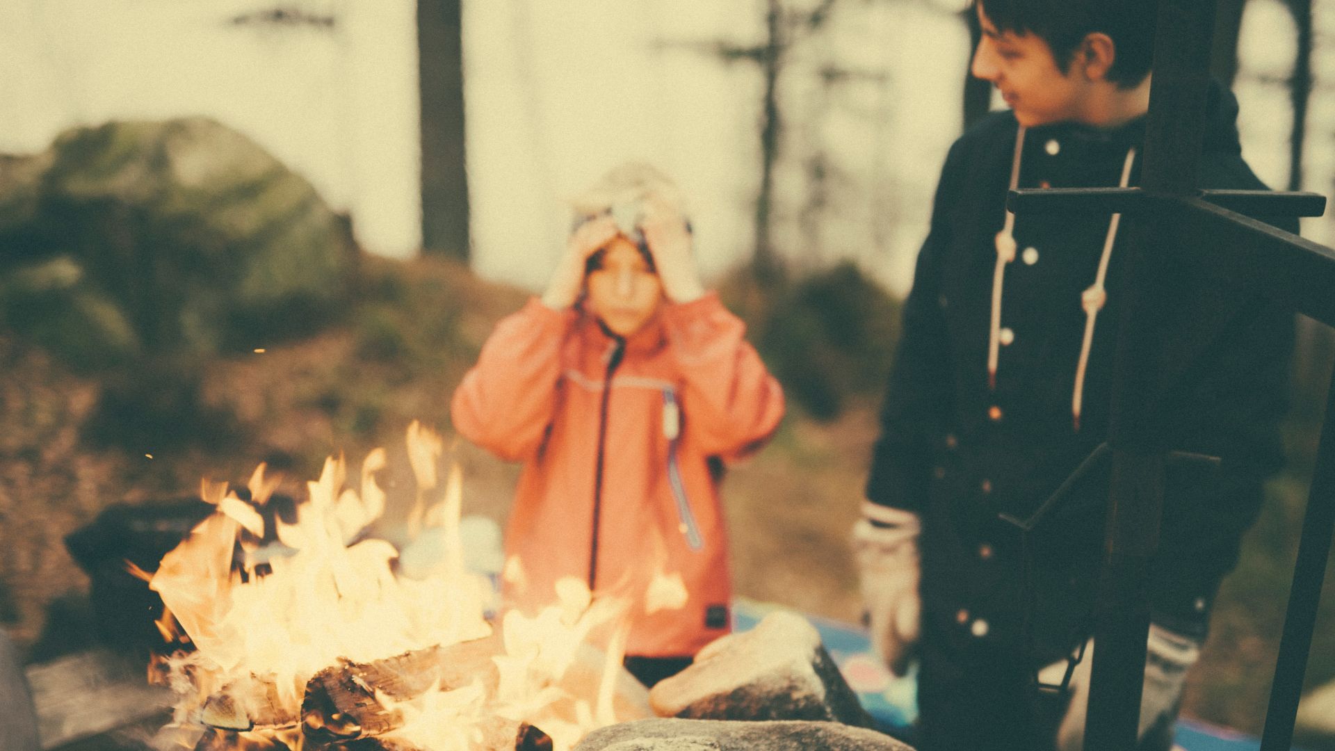 man in black sweatshirt standing in front of fire place surrounded by rocks during daytime