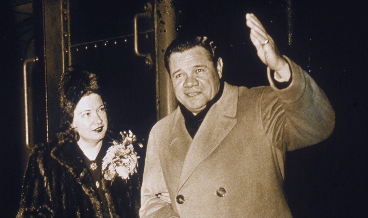 Gettyimages - 88374932, Mr & Mrs Babe Ruth On The Train American baseball player George Herman 'Babe' Ruth (1895 - 1948), dressed in an overcoat, holds a cigar and waves as his wife, Claire Merritt Hodgson, in a fur coat and matching hat, stands beside him on a train, late 1930s or early 1940s.