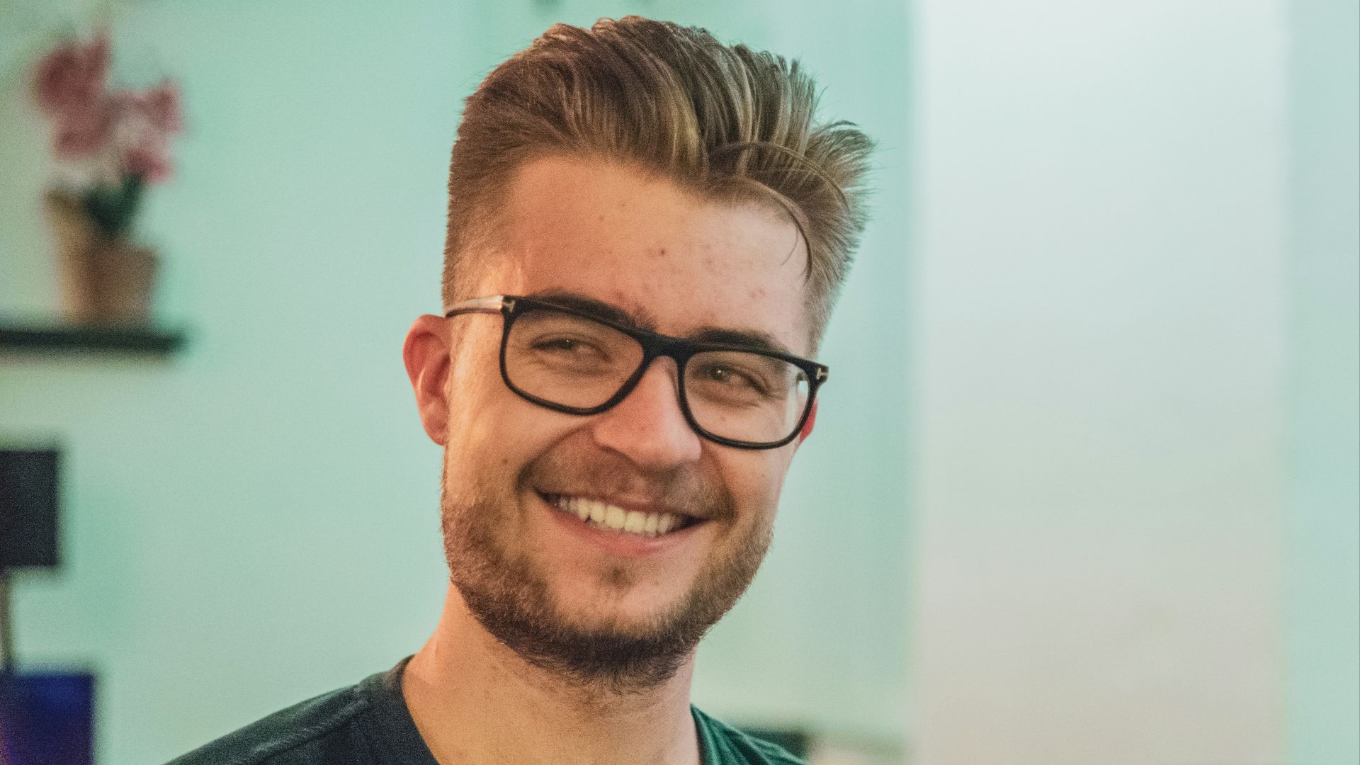 man wearing green crew-neck top and eyeglasses with black frames looking at side