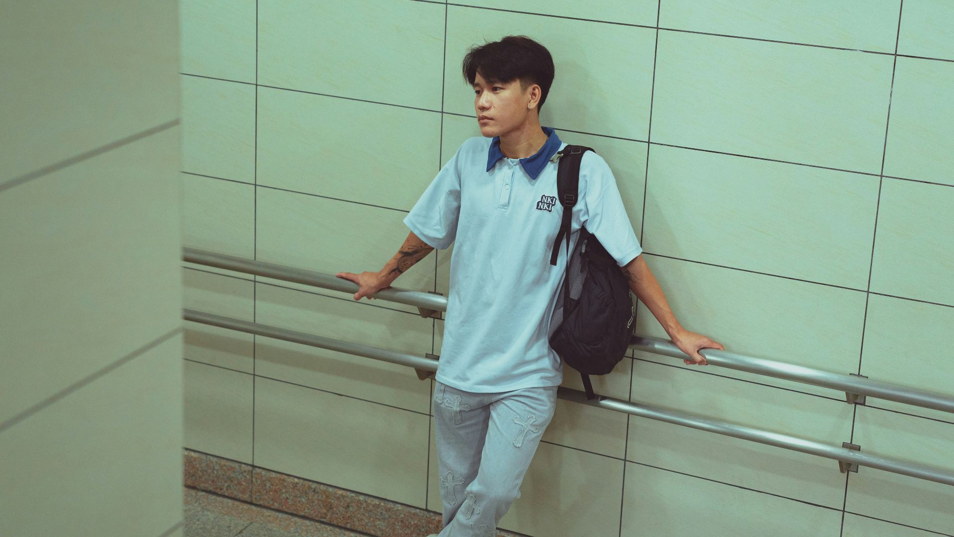 A man leaning against a wall with a backpack