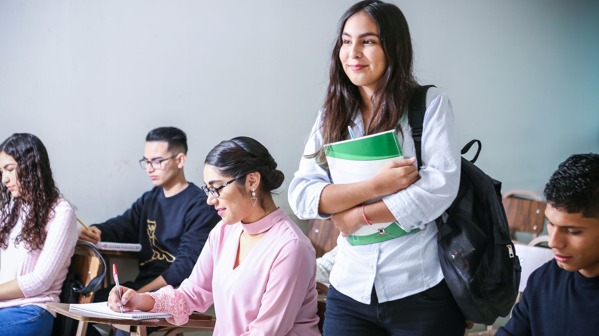 woman carrying white and green textbook