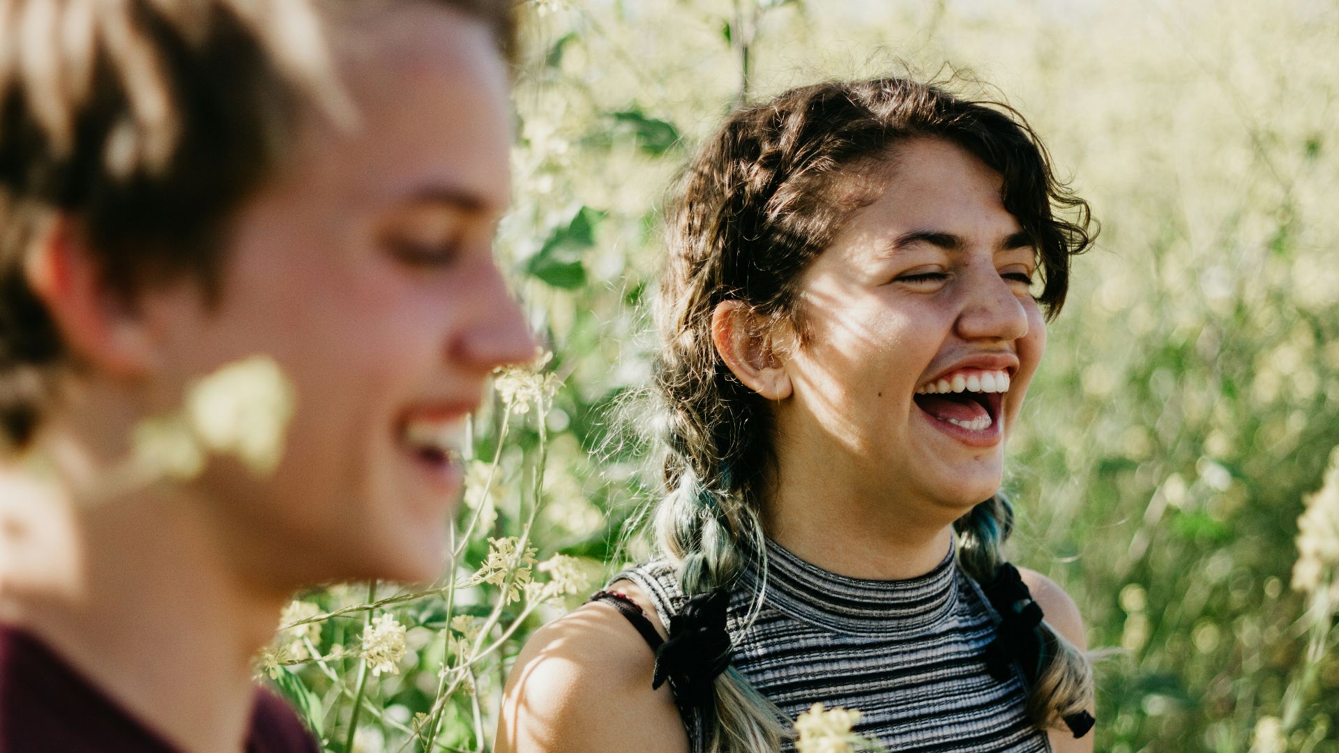 man and woman laughing surrounded with green grass during daytime