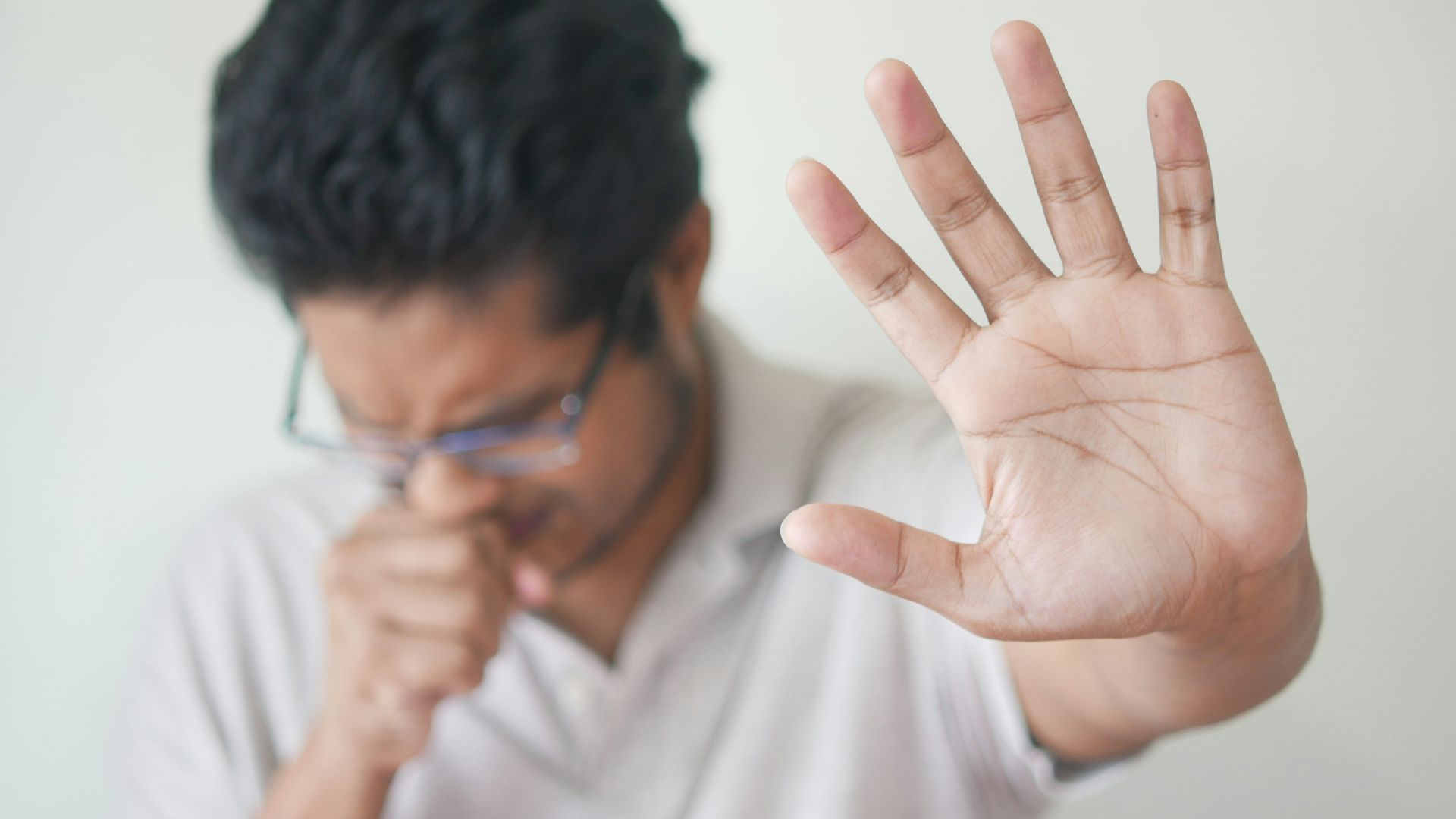 a man holding his hand up in front of his face