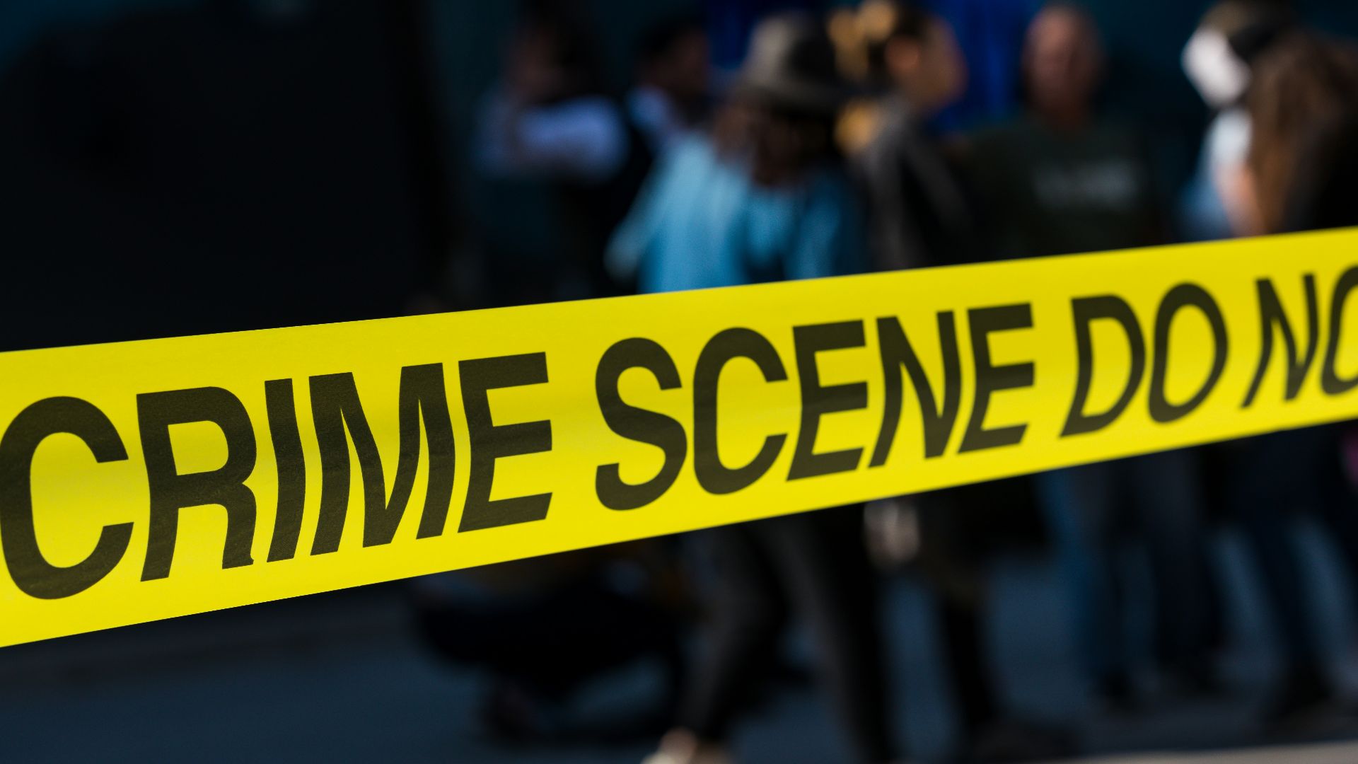 a group of people standing next to a yellow police line