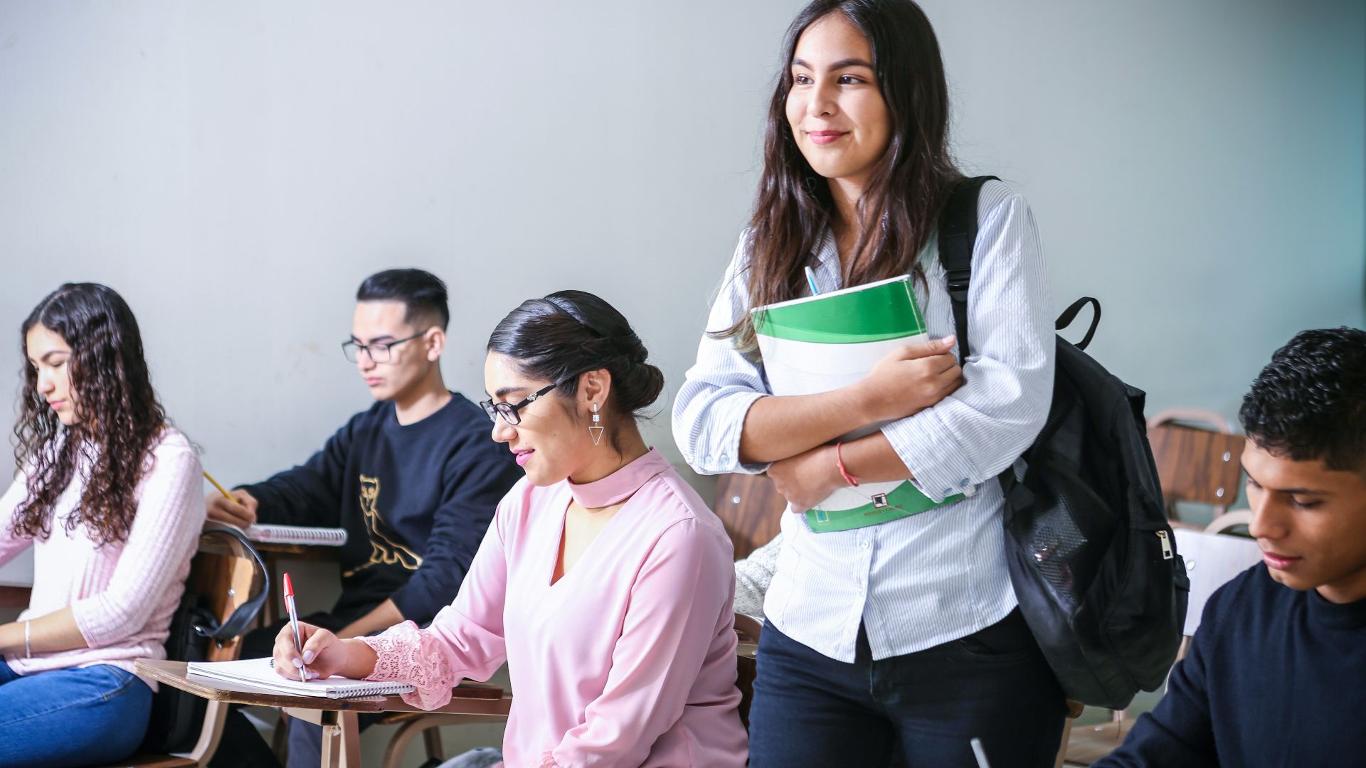 woman carrying white and green textbook