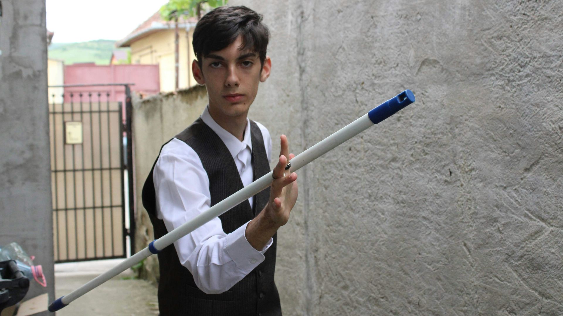 a boy in a vest and tie holding an umbrella