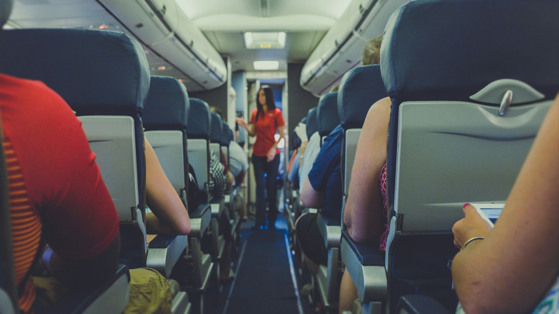 flight attendant standing between passenger seat