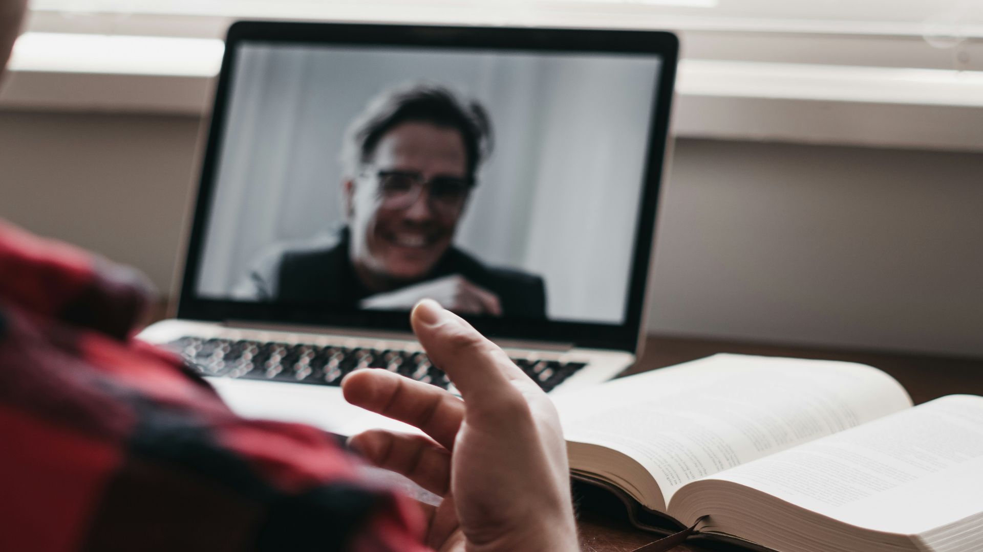 person in red and black plaid long sleeve shirt using black laptop computer