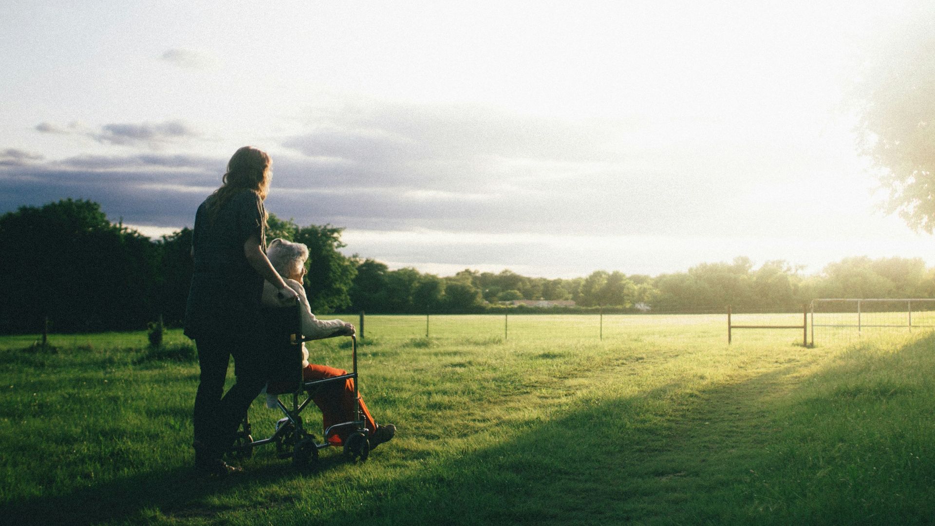 woman standing next to woman riding wheelchair